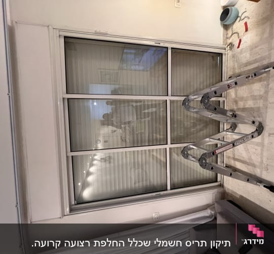 תריסים סגורים על חלון גדול עם סולם לידם